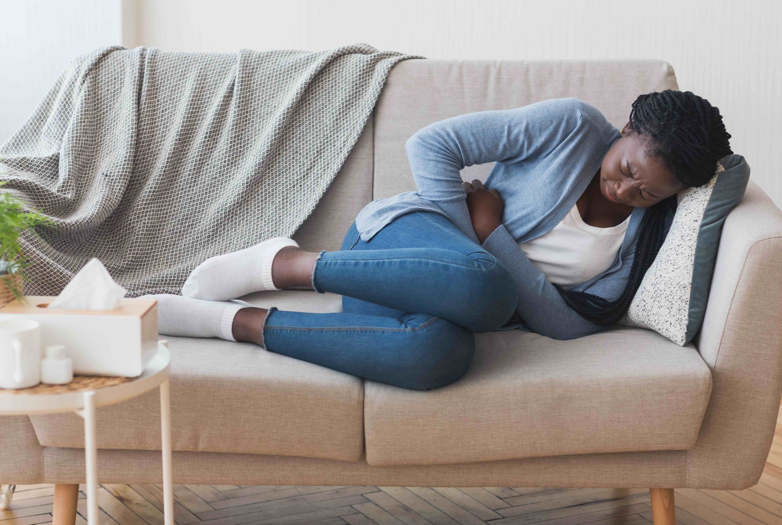 Menstrual Pain. Sick Young Black Woman Lying On Couch At Home Suffering From Abdominal Ache